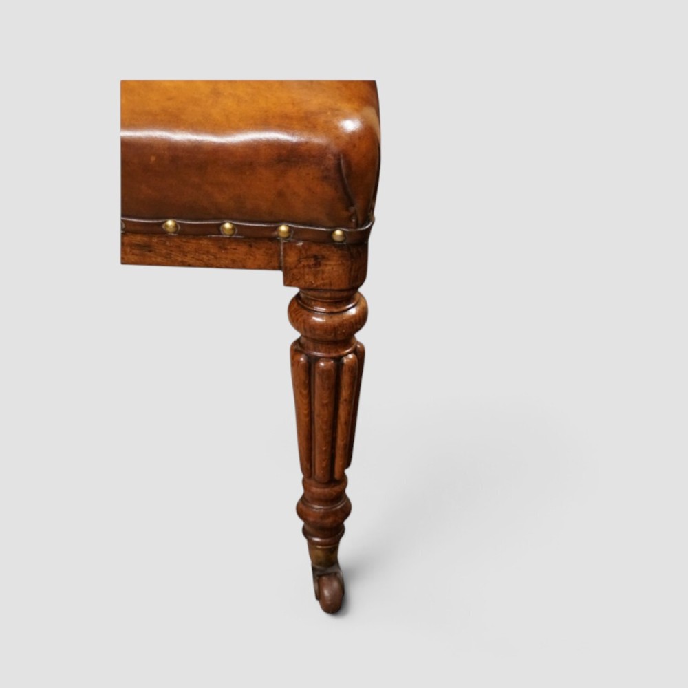 A set of four Victorian oak dining chairs featuring arched gothic-style backrests upholstered in warm brown leather with brass stud trim. View III