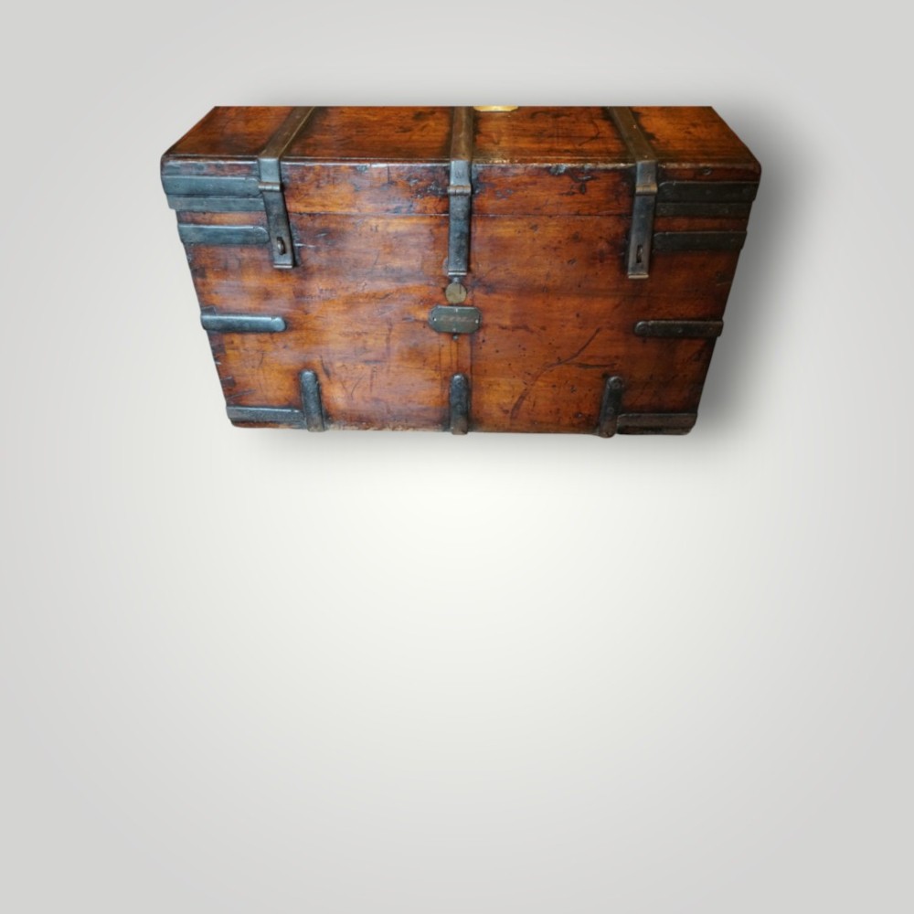 A rectangular antique walnut wood trunk featuring heavy iron binding straps, metal corner hardware, and a brass plaque on the lid. View V