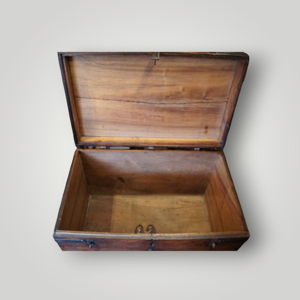 A rectangular antique walnut wood trunk featuring heavy iron binding straps, metal corner hardware, and a brass plaque on the lid. View VII