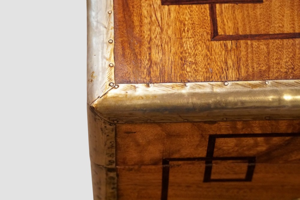 A rectangular Victorian camphor wood campaign chest featuring polished brass binding along the edges, geometric dark line inlay, and a central brass lock escutcheon. View II