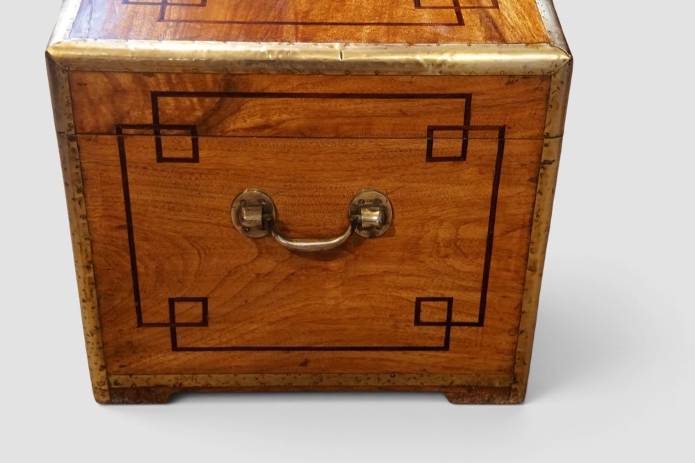 A rectangular Victorian camphor wood campaign chest featuring polished brass binding along the edges, geometric dark line inlay, and a central brass lock escutcheon. View V