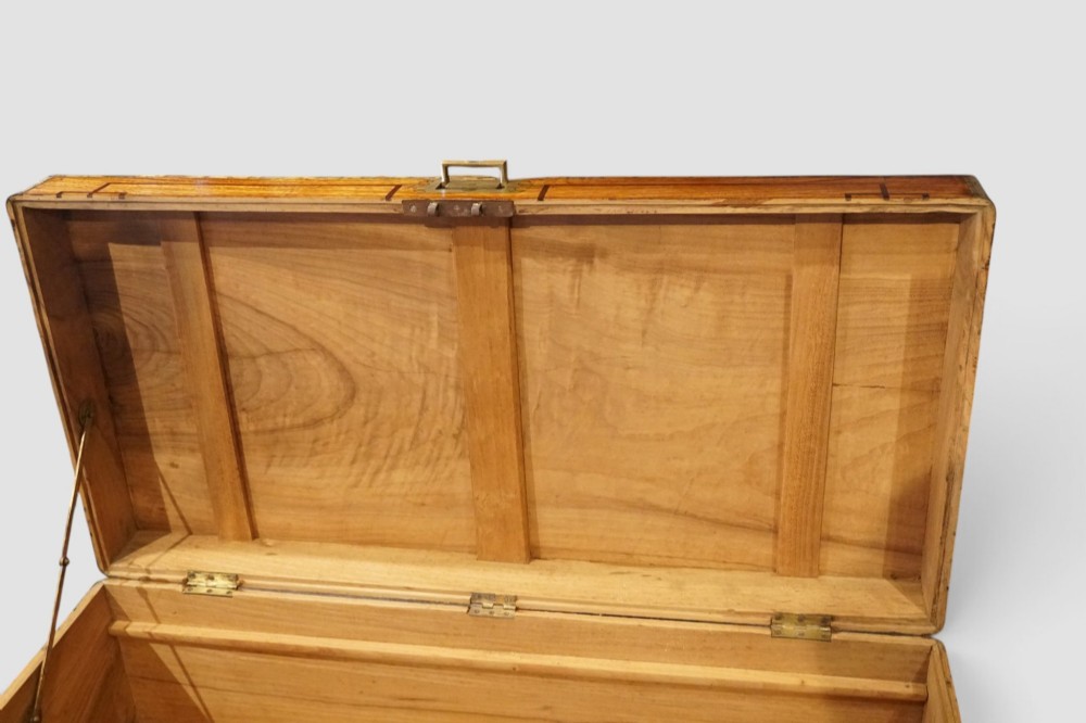 A rectangular Victorian camphor wood campaign chest featuring polished brass binding along the edges, geometric dark line inlay, and a central brass lock escutcheon. View X