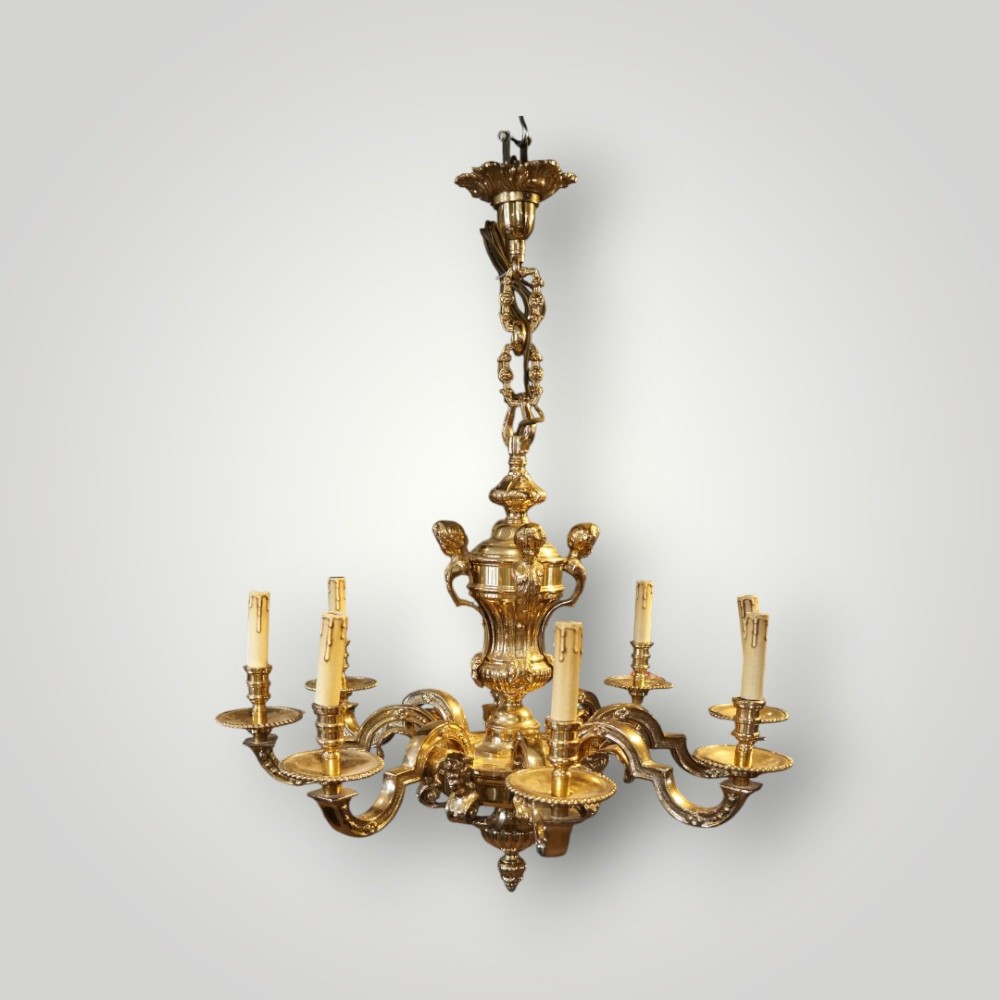 A nineteenth-century French gilt bronze eight-light chandelier featuring a central urn column and scrolling candle arms with faux candle sleeves.