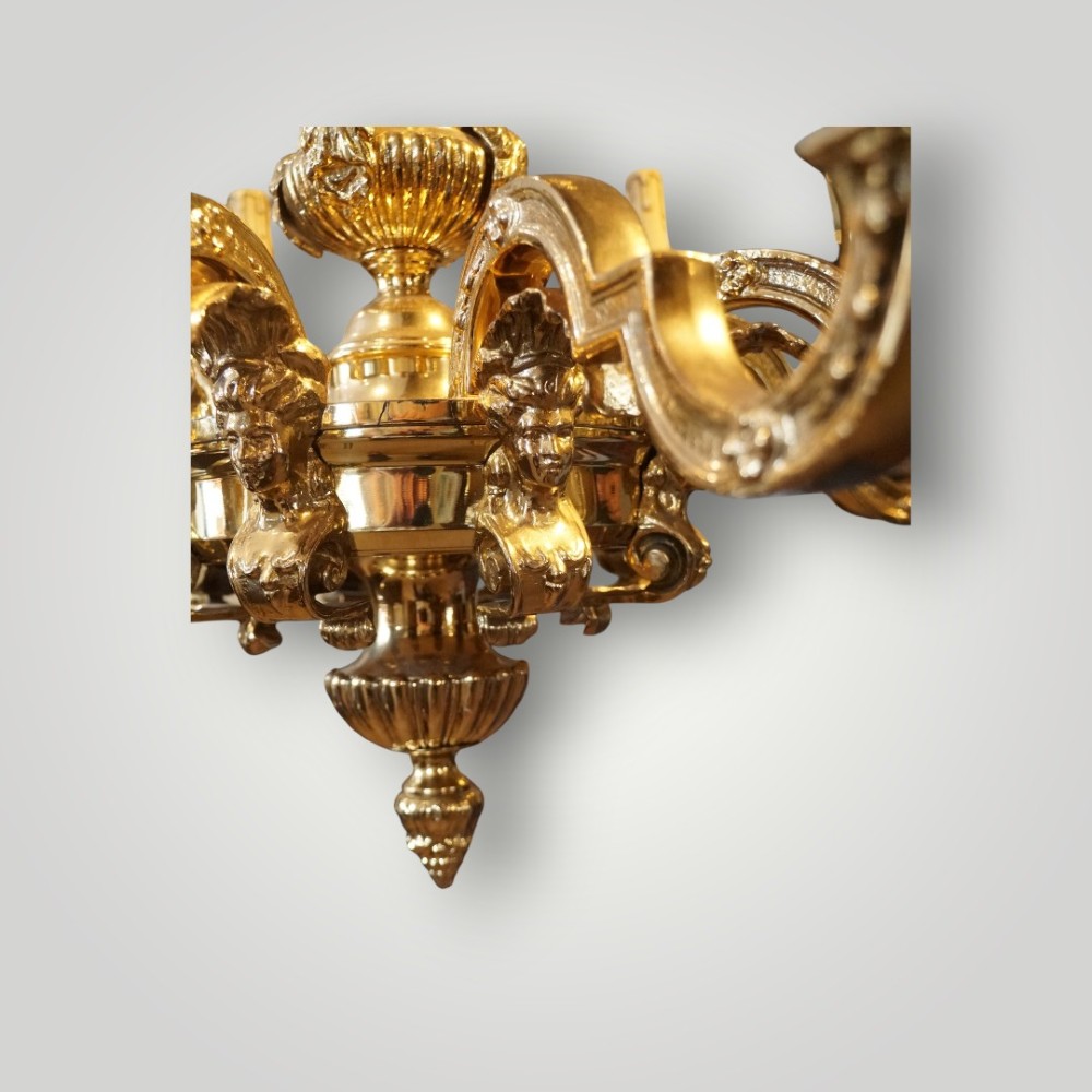 A nineteenth-century French gilt bronze eight-light chandelier featuring a central urn column and scrolling candle arms with faux candle sleeves. View III