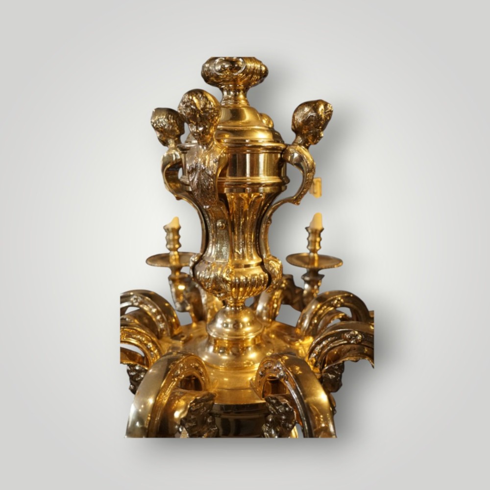 A nineteenth-century French gilt bronze eight-light chandelier featuring a central urn column and scrolling candle arms with faux candle sleeves. View IX
