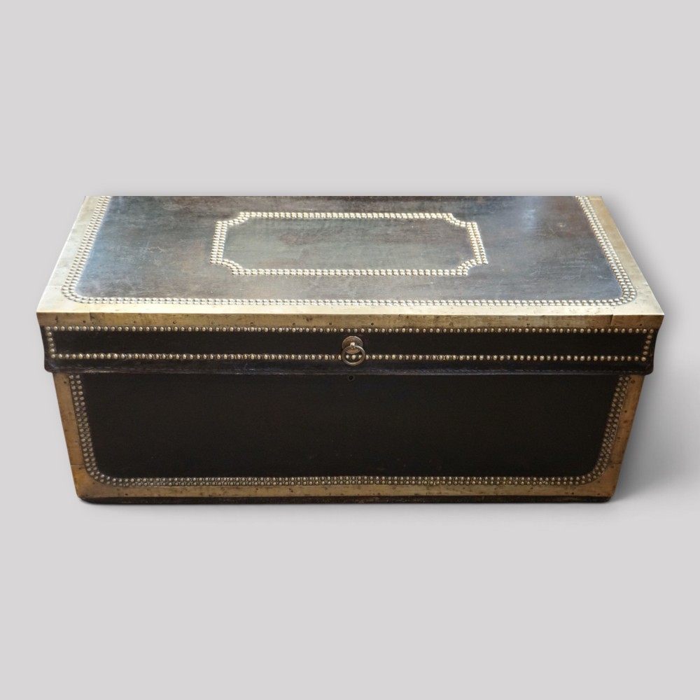 An antique dark green leather trunk featuring brass corner straps, close-studded brass borders, and a brass keyhole escutcheon. View V