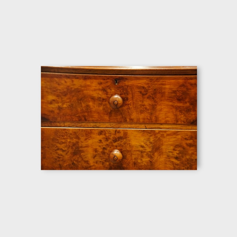 A 19th-century Victorian burr walnut linen press featuring an upper cabinet with arched panel doors over a chest of four drawers with turned wooden knobs. View VII
