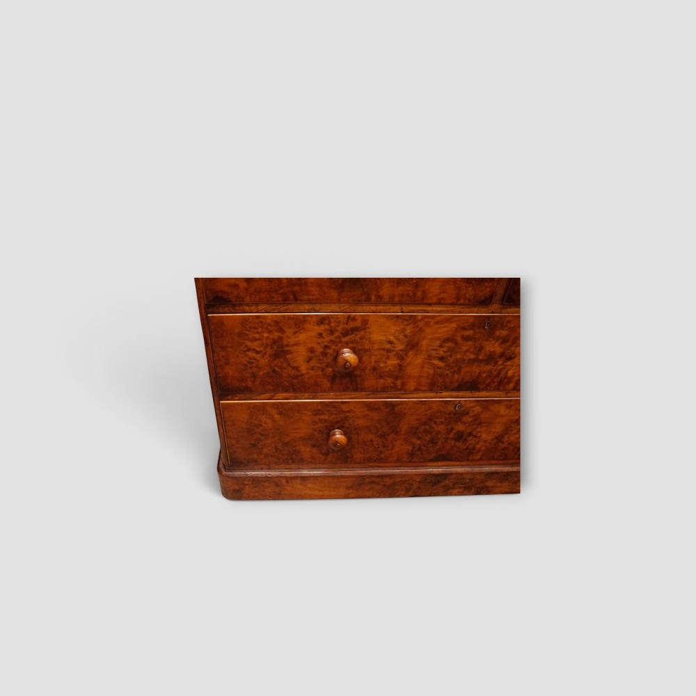 A 19th-century Victorian burr walnut linen press featuring an upper cabinet with arched panel doors over a chest of four drawers with turned wooden knobs. View IX