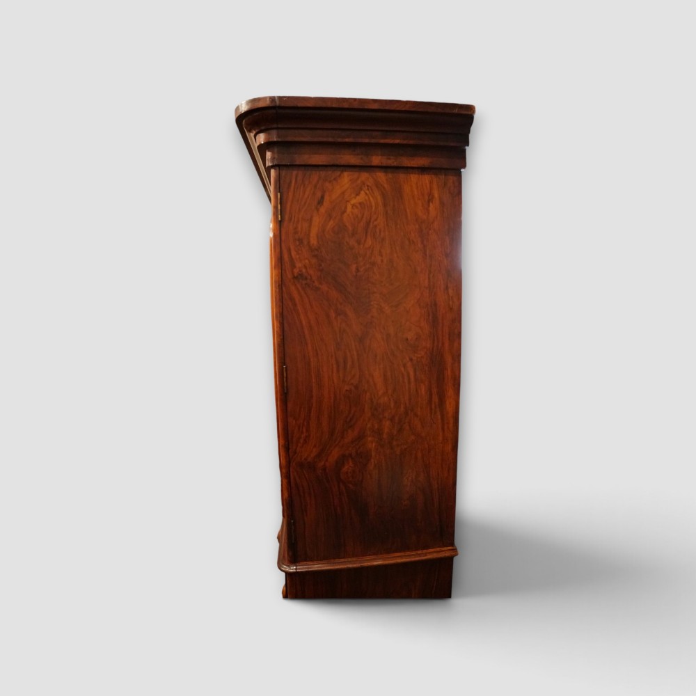 A 19th-century Victorian burr walnut linen press featuring an upper cabinet with arched panel doors over a chest of four drawers with turned wooden knobs. View XII