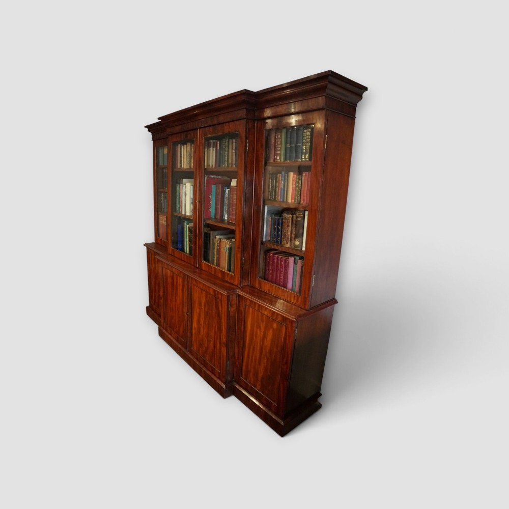 A 19th-century mahogany breakfront bookcase featuring glazed upper doors filled with books above solid panelled cupboard doors. View II