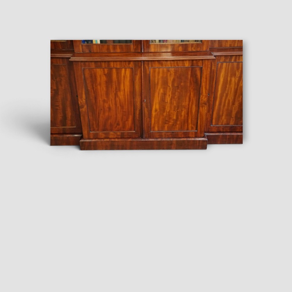 A 19th-century mahogany breakfront bookcase featuring glazed upper doors filled with books above solid panelled cupboard doors. View III
