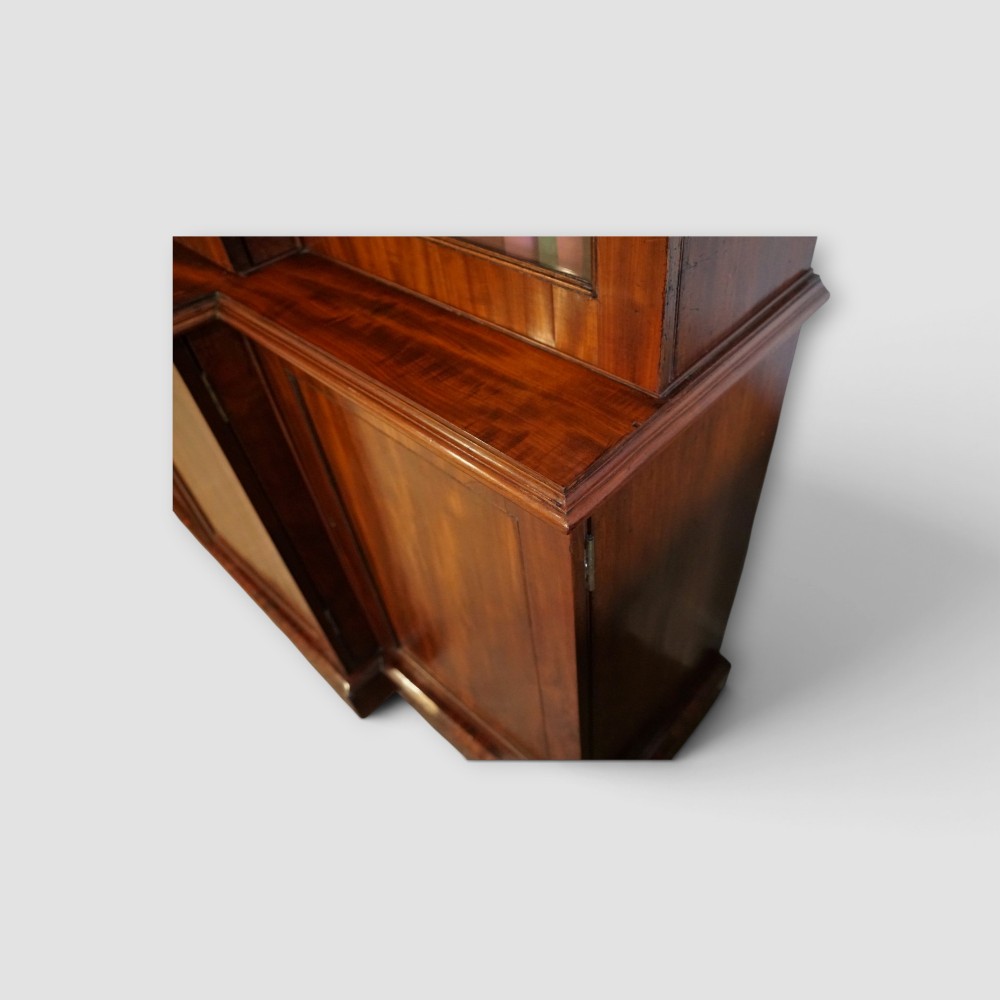 A 19th-century mahogany breakfront bookcase featuring glazed upper doors filled with books above solid panelled cupboard doors. View V