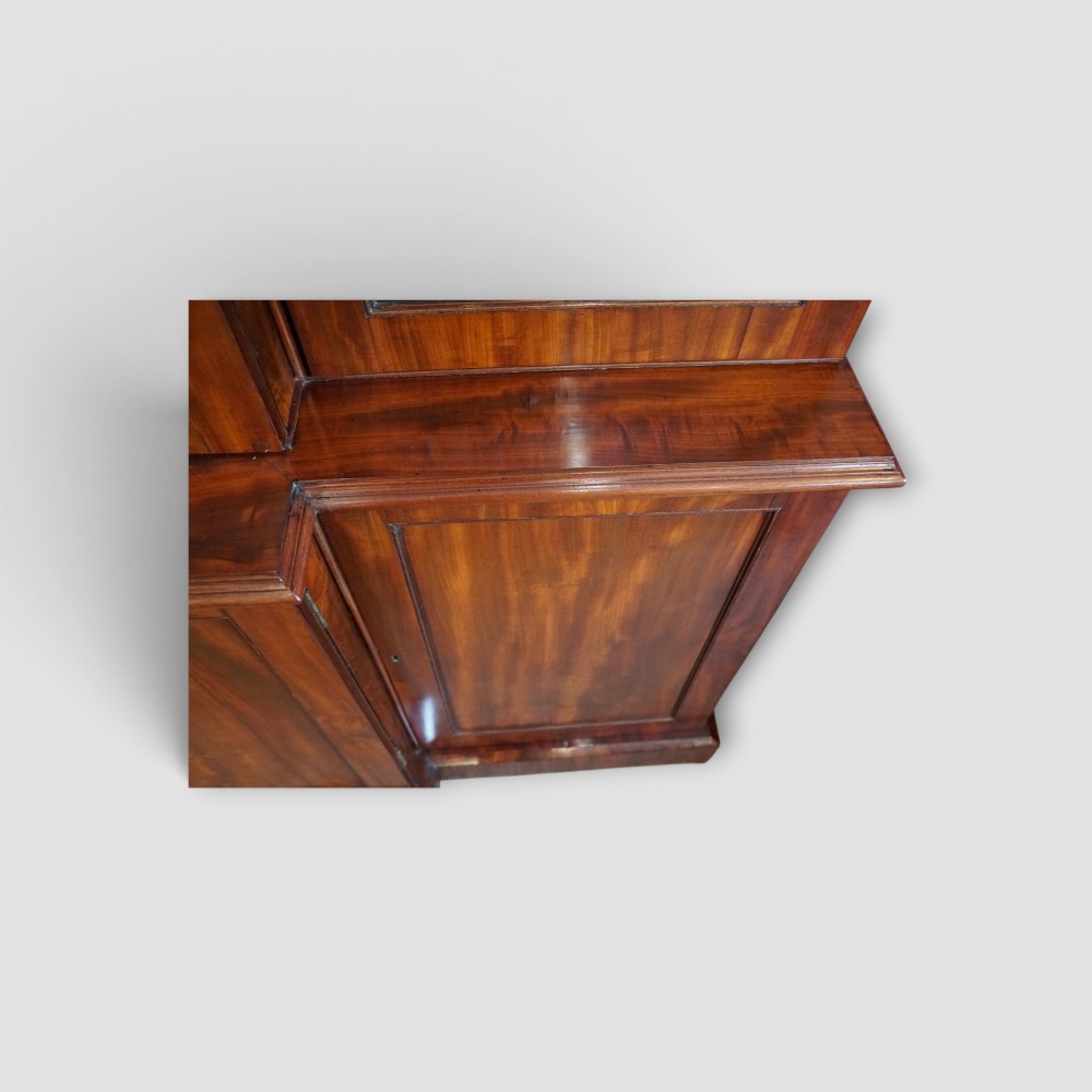 A 19th-century mahogany breakfront bookcase featuring glazed upper doors filled with books above solid panelled cupboard doors. View VII