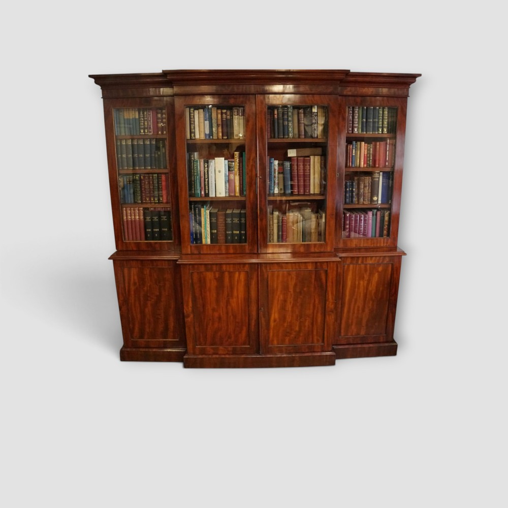 A 19th-century mahogany breakfront bookcase featuring glazed upper doors filled with books above solid panelled cupboard doors. View X