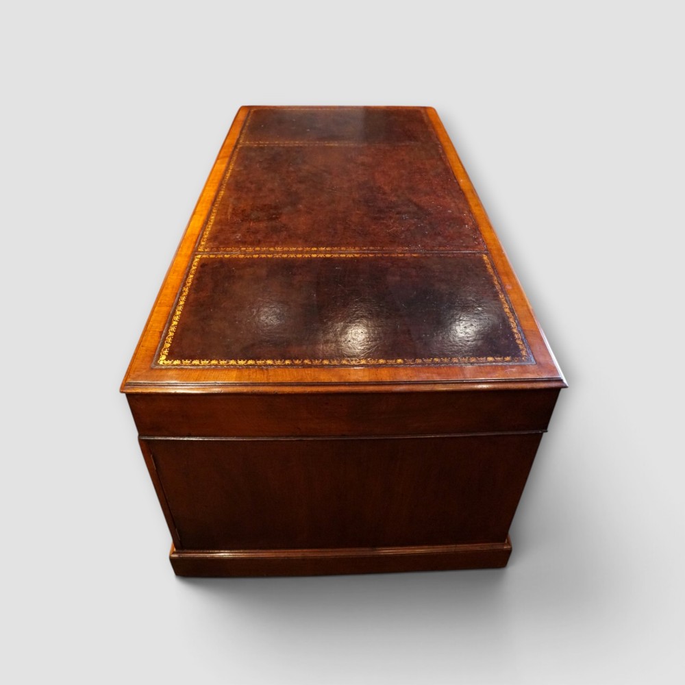 A large Victorian mahogany partners desk featuring a brown leather inset writing surface, twin drawer pedestals, brass swan-neck handles, and a wide central kneehole. View IV