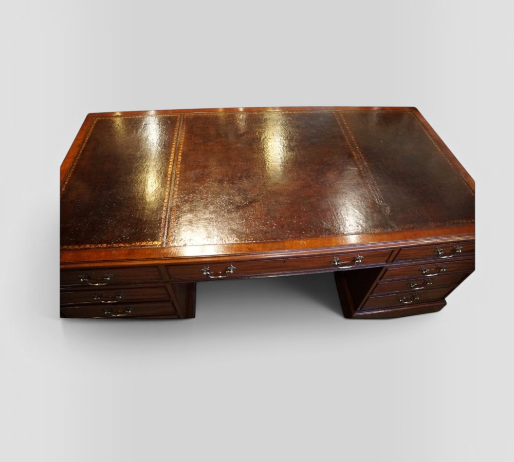 A large Victorian mahogany partners desk featuring a brown leather inset writing surface, twin drawer pedestals, brass swan-neck handles, and a wide central kneehole. View VII
