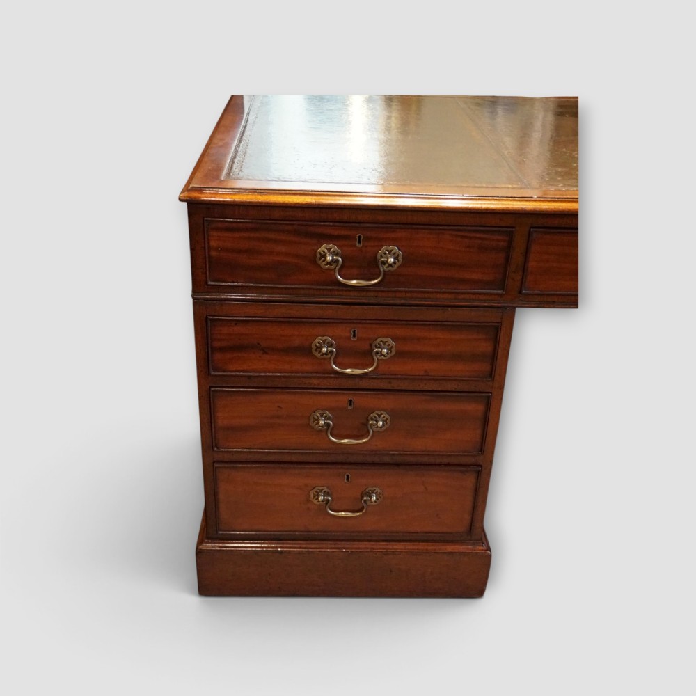 A large Victorian mahogany partners desk featuring a brown leather inset writing surface, twin drawer pedestals, brass swan-neck handles, and a wide central kneehole. View VIII