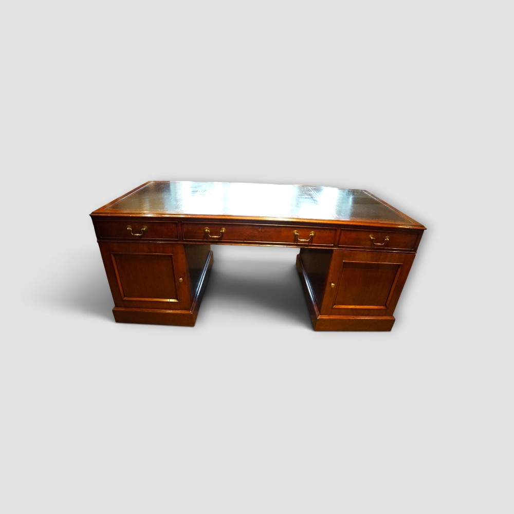 A large Victorian mahogany partners desk featuring a brown leather inset writing surface, twin drawer pedestals, brass swan-neck handles, and a wide central kneehole. View X