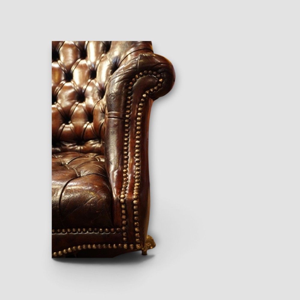A deep buttoned brown leather captains desk chair with brass studding trim and a dark mahogany swivel base on castors. View II