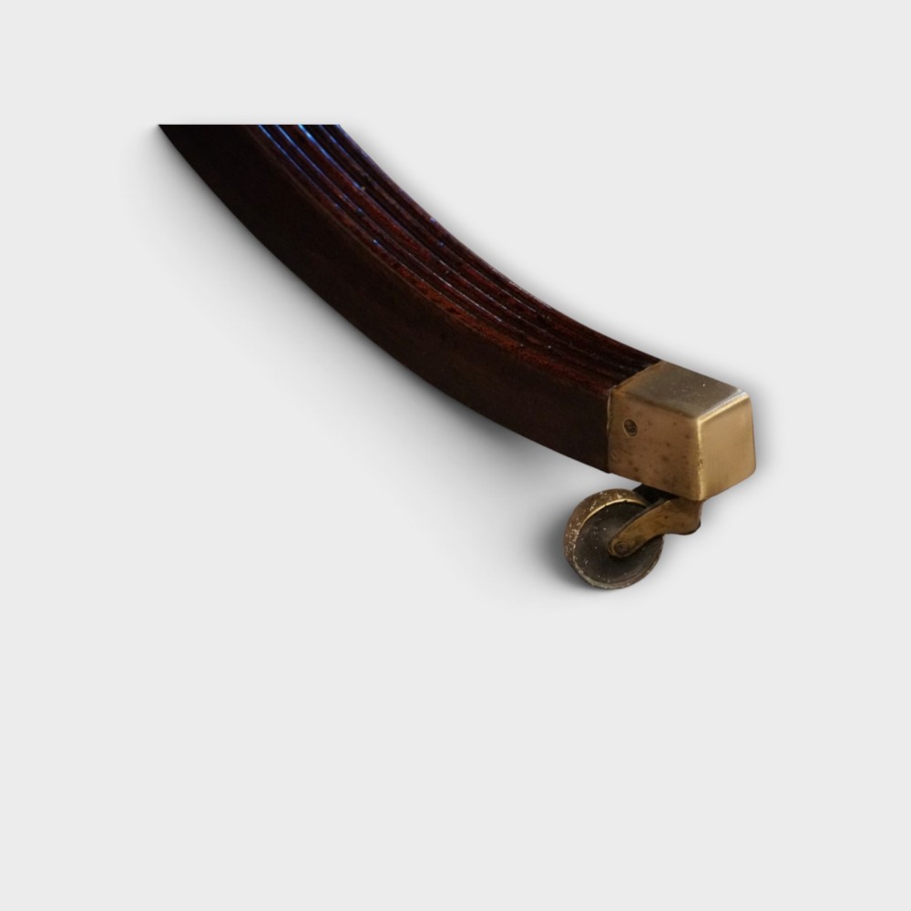 A Georgian style dark mahogany dining table featuring an extendable top, twin turned pedestal pillars, and splayed quadruped legs with brass toe caps. View III