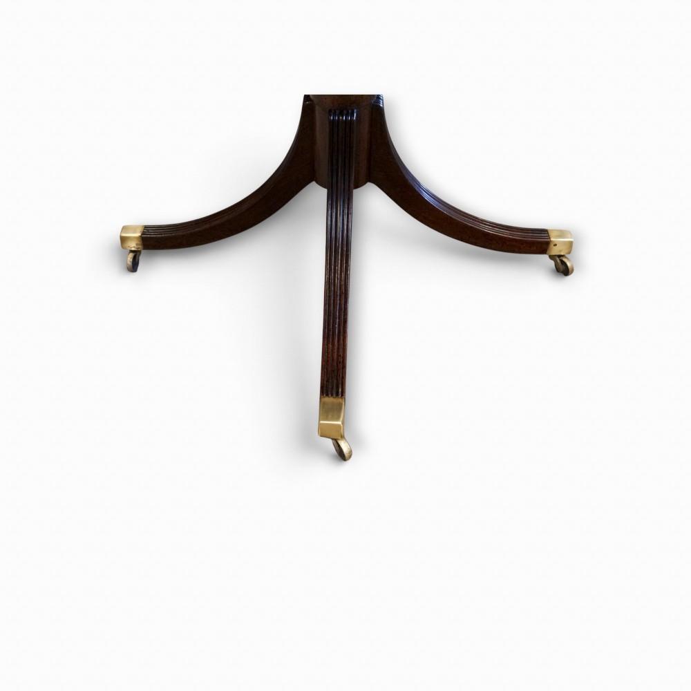 A Georgian style dark mahogany dining table featuring an extendable top, twin turned pedestal pillars, and splayed quadruped legs with brass toe caps. View VI
