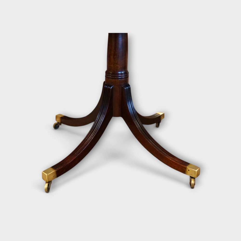 A Georgian style dark mahogany dining table featuring an extendable top, twin turned pedestal pillars, and splayed quadruped legs with brass toe caps. View VIII