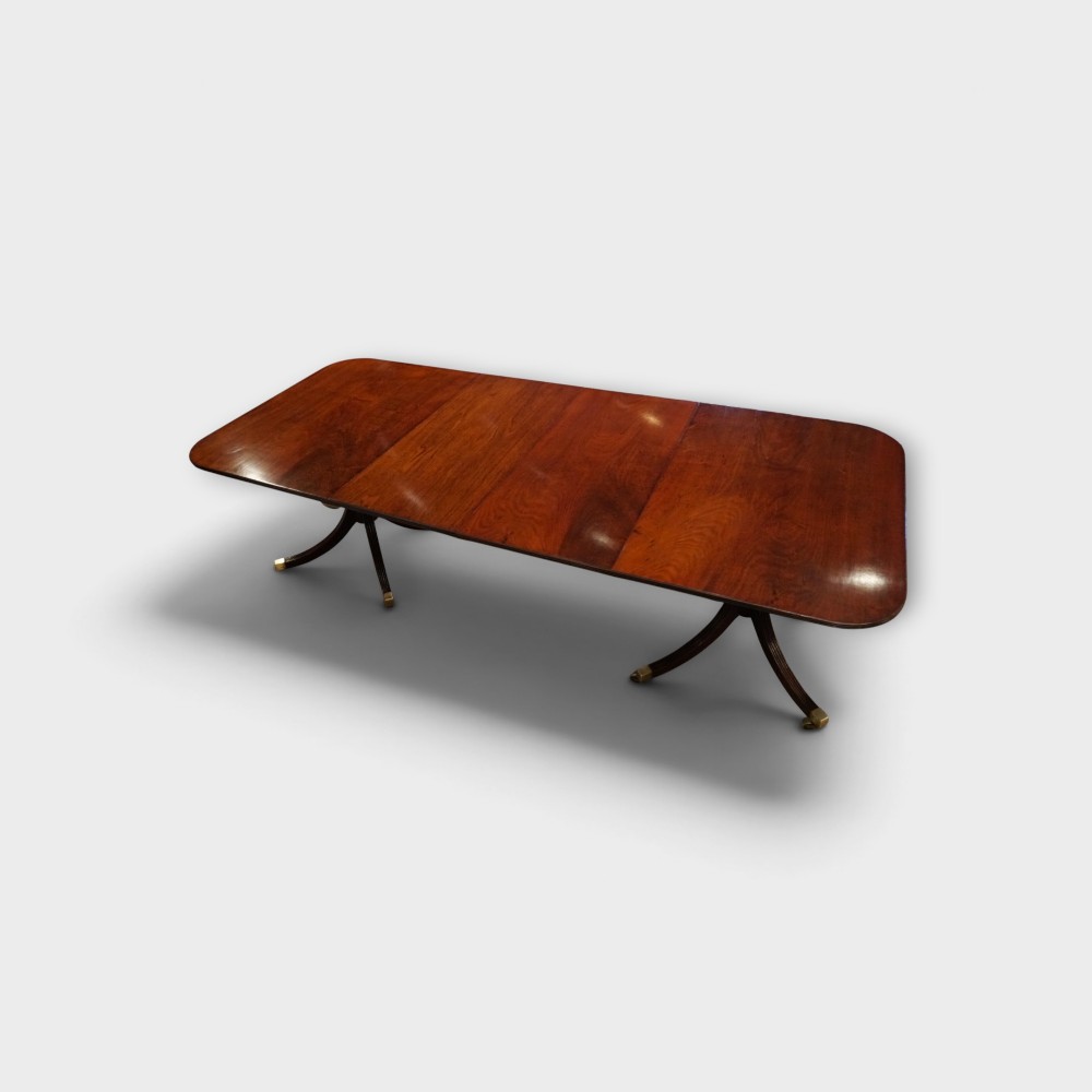 A Georgian style dark mahogany dining table featuring an extendable top, twin turned pedestal pillars, and splayed quadruped legs with brass toe caps. View XI