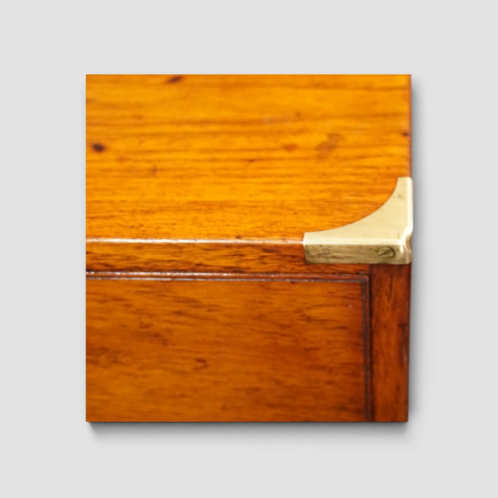 A Victorian teak two-part military campaign chest of drawers featuring flush brass handles, brass corner mounts, and turned feet. View III
