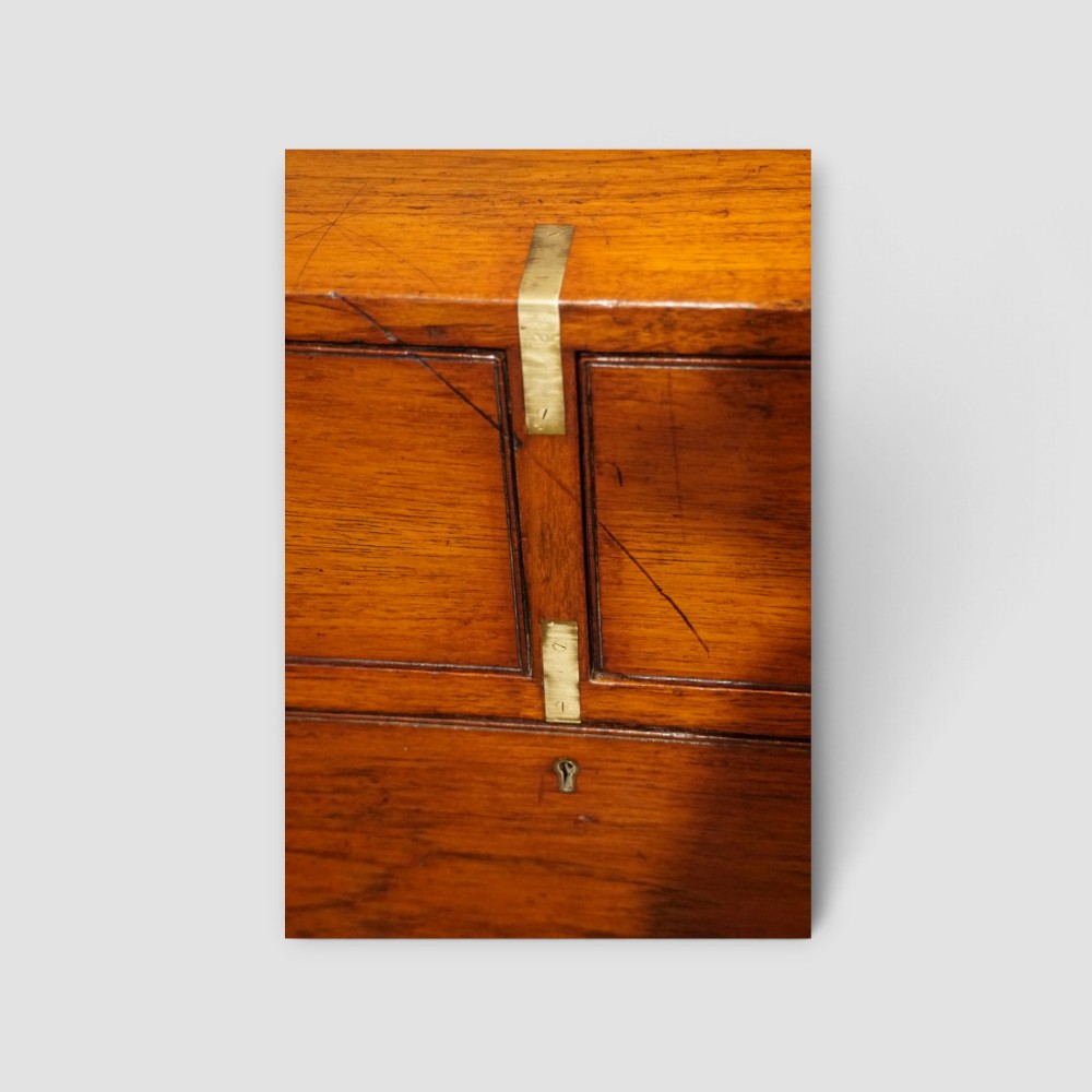 A Victorian teak two-part military campaign chest of drawers featuring flush brass handles, brass corner mounts, and turned feet. View IX