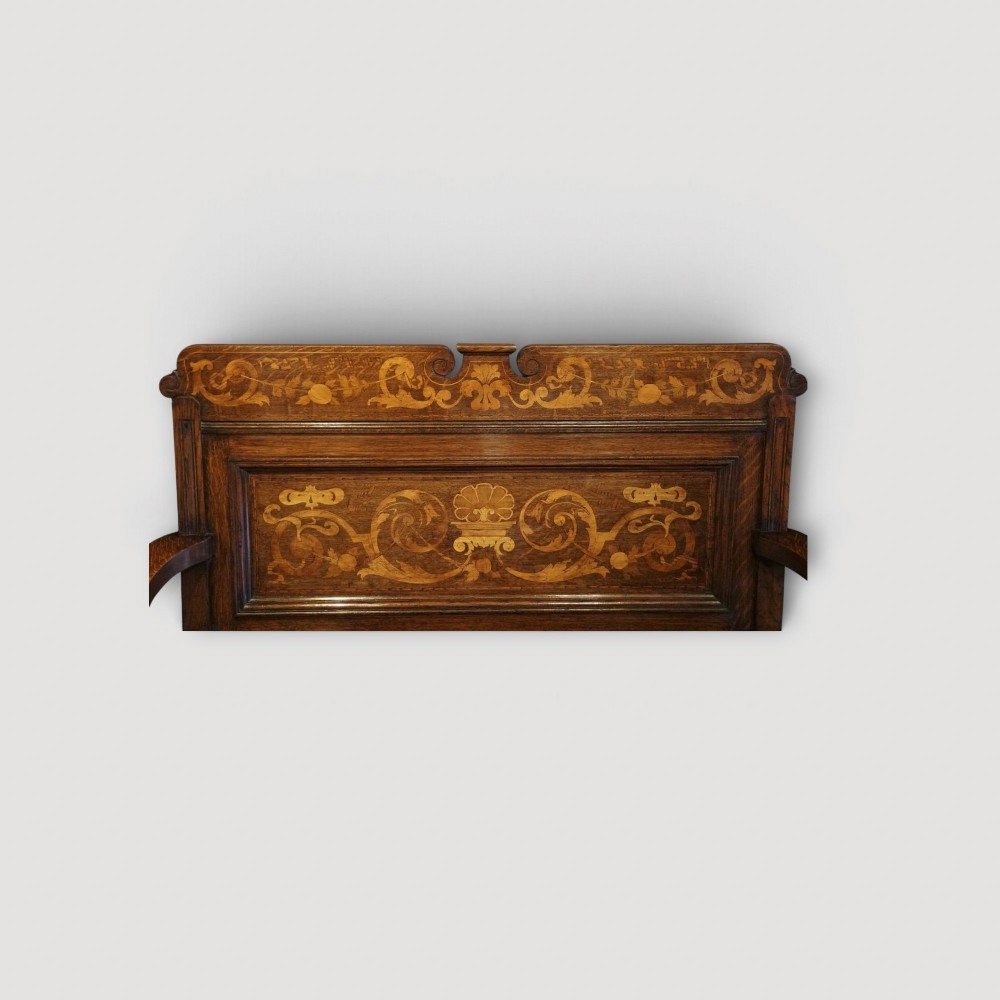 An Art Nouveau solid oak settle featuring decorative marquetry inlay across the backrest and lower front panels, curved armrests, and a lift-up storage seat. View IV