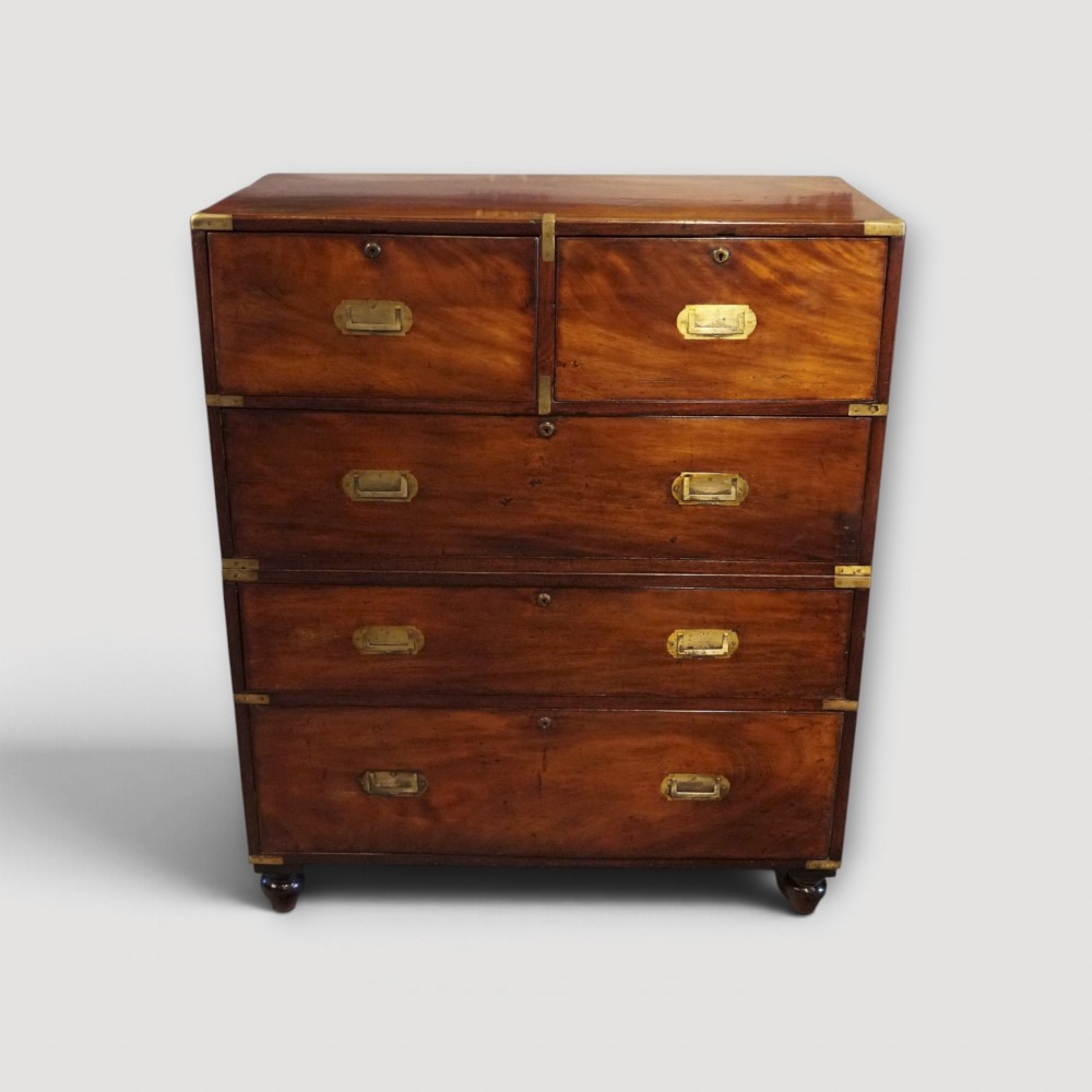 A Victorian mahogany campaign chest featuring two short drawers over three long drawers with flush brass handles, brass corner brackets, and turned feet.