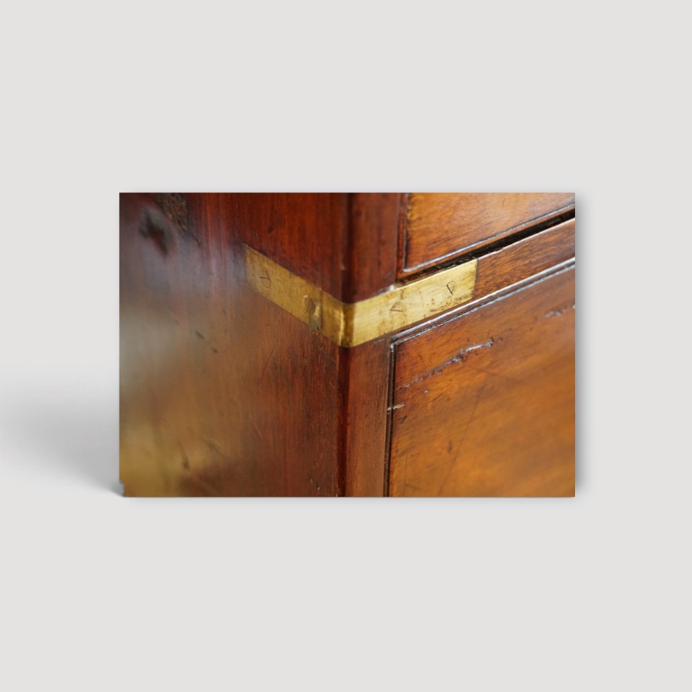 A Victorian mahogany campaign chest featuring two short drawers over three long drawers with flush brass handles, brass corner brackets, and turned feet. View III