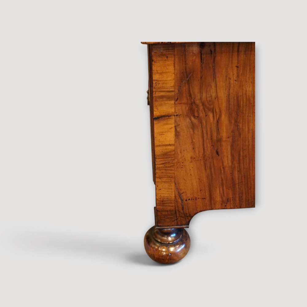 An antique Queen Anne walnut chest-on-chest in two sections featuring a multi-drawer configuration, figured grain patterns, brass drop handles, and bun feet. View IV
