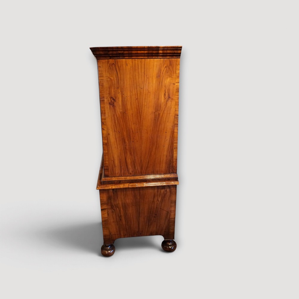 An antique Queen Anne walnut chest-on-chest in two sections featuring a multi-drawer configuration, figured grain patterns, brass drop handles, and bun feet. View X