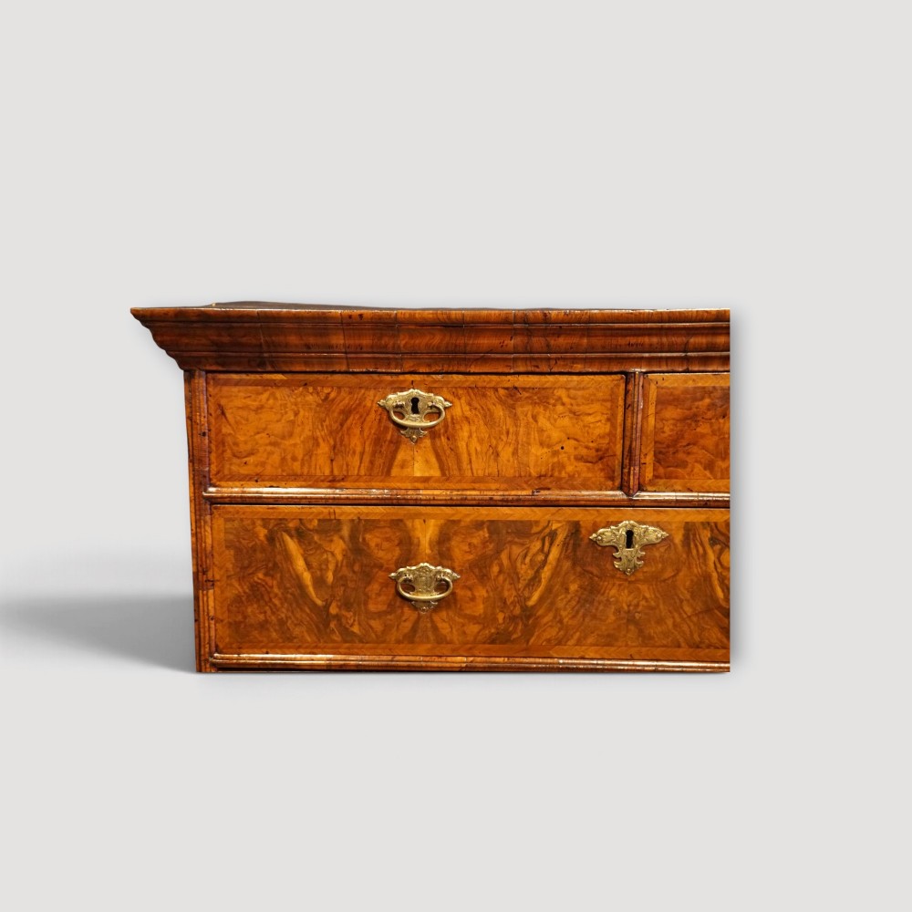 An antique Queen Anne walnut chest-on-chest in two sections featuring a multi-drawer configuration, figured grain patterns, brass drop handles, and bun feet. View XI