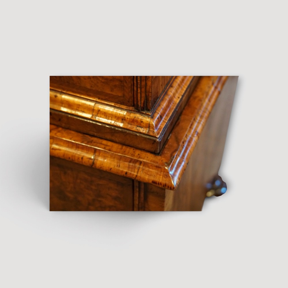 An antique Queen Anne walnut chest-on-chest in two sections featuring a multi-drawer configuration, figured grain patterns, brass drop handles, and bun feet. View XII