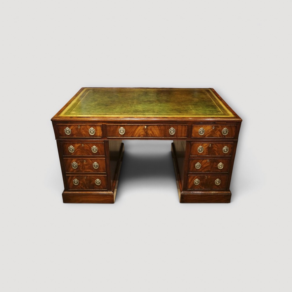 A Victorian mahogany partners desk featuring a green leather writing surface, dual pedestals with drawers, and round brass handles.