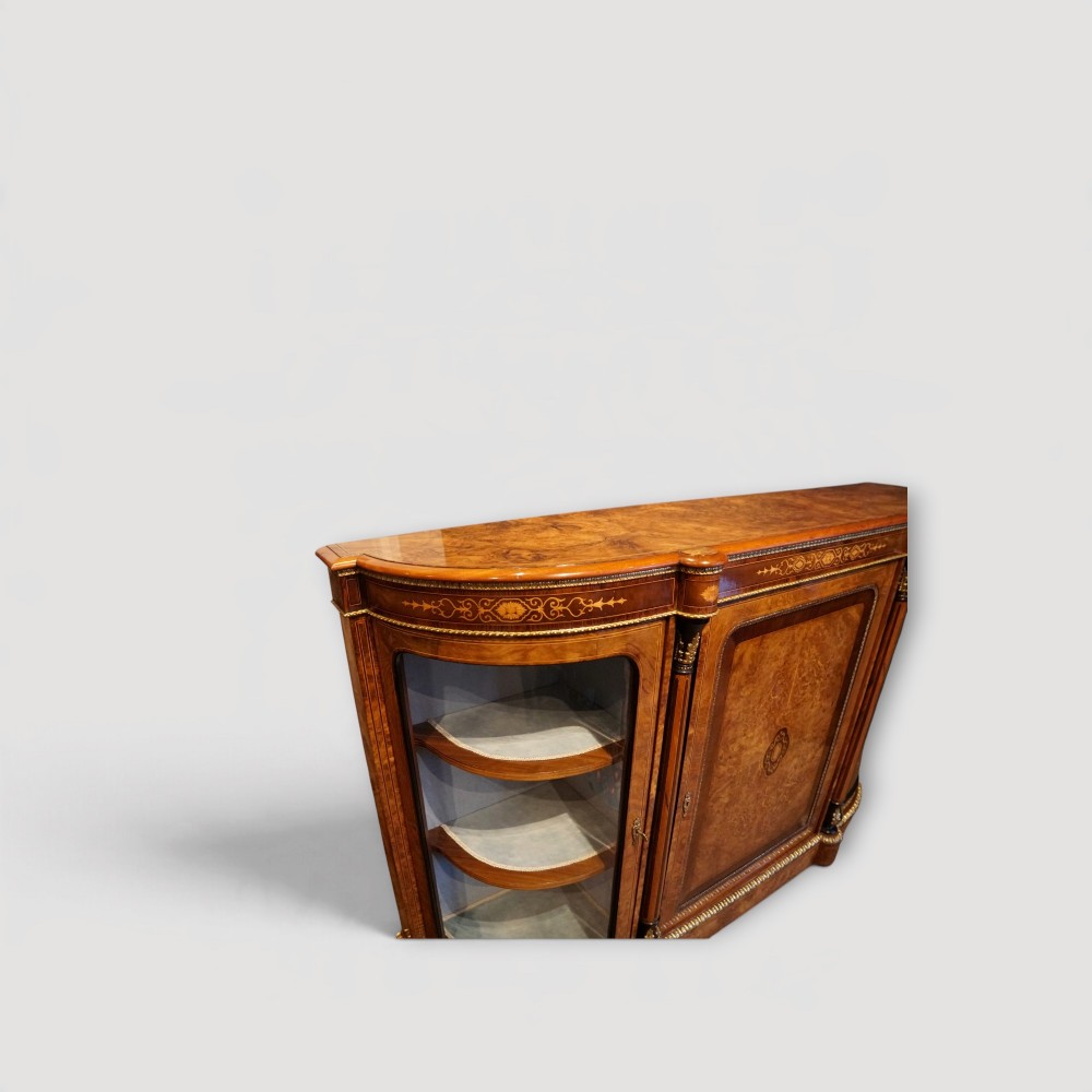 A Victorian burr walnut credenza featuring a central marquetry inlaid door flanked by two curved glazed display side cabinets with gilt mounts. View II
