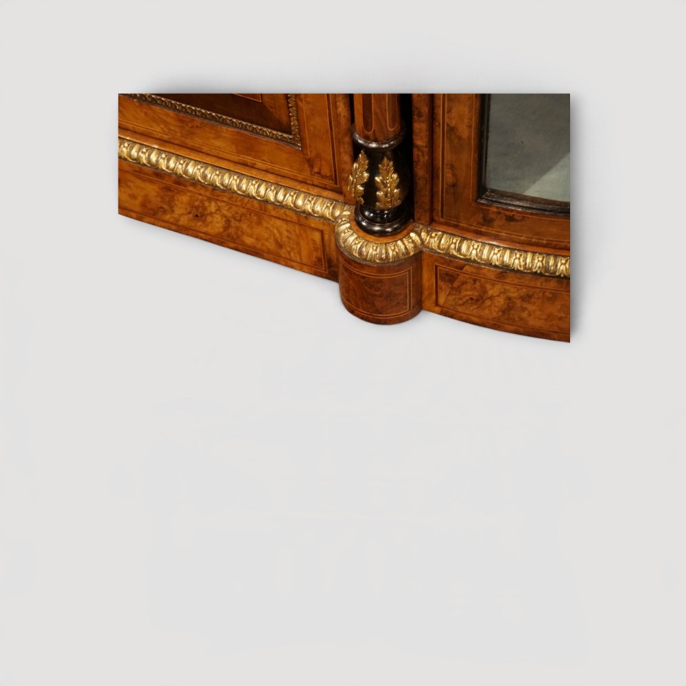 A Victorian burr walnut credenza featuring a central marquetry inlaid door flanked by two curved glazed display side cabinets with gilt mounts. View III