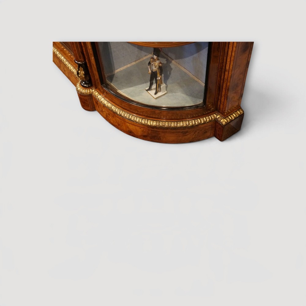 A Victorian burr walnut credenza featuring a central marquetry inlaid door flanked by two curved glazed display side cabinets with gilt mounts. View IV