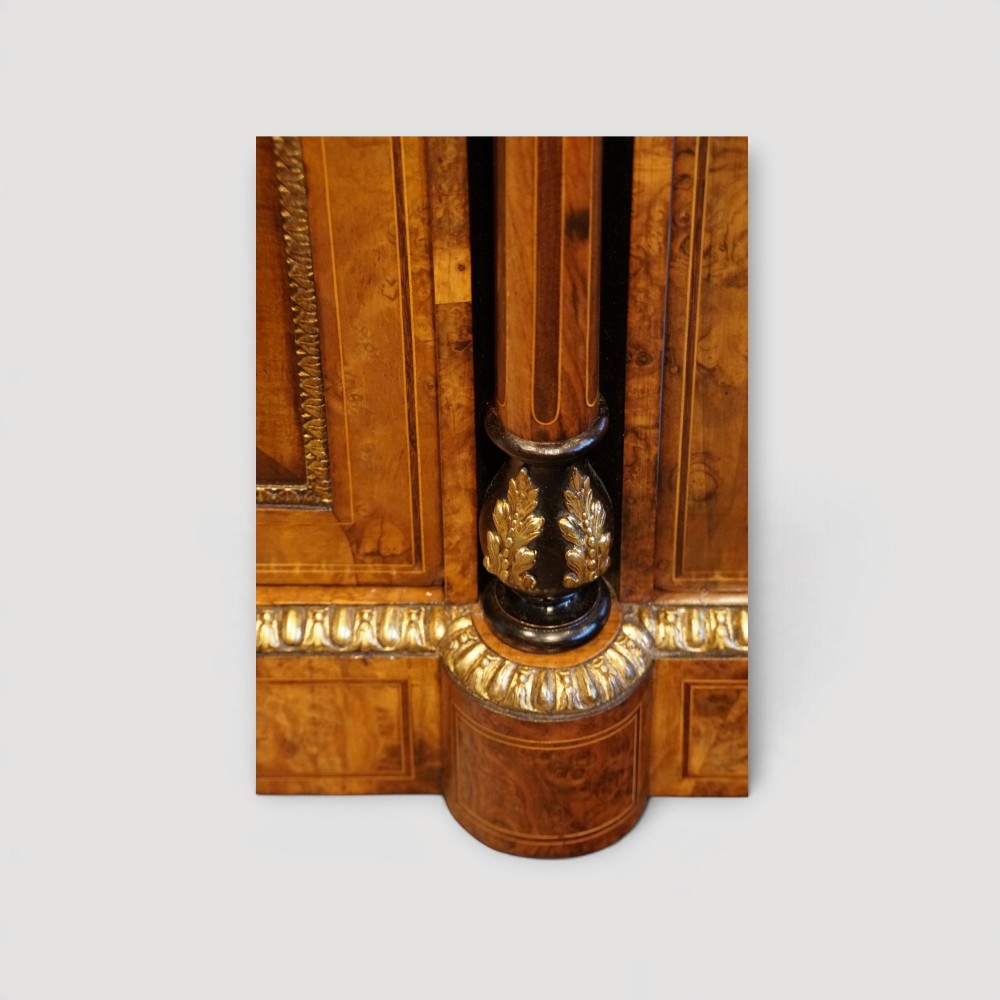 A Victorian burr walnut credenza featuring a central marquetry inlaid door flanked by two curved glazed display side cabinets with gilt mounts. View VI