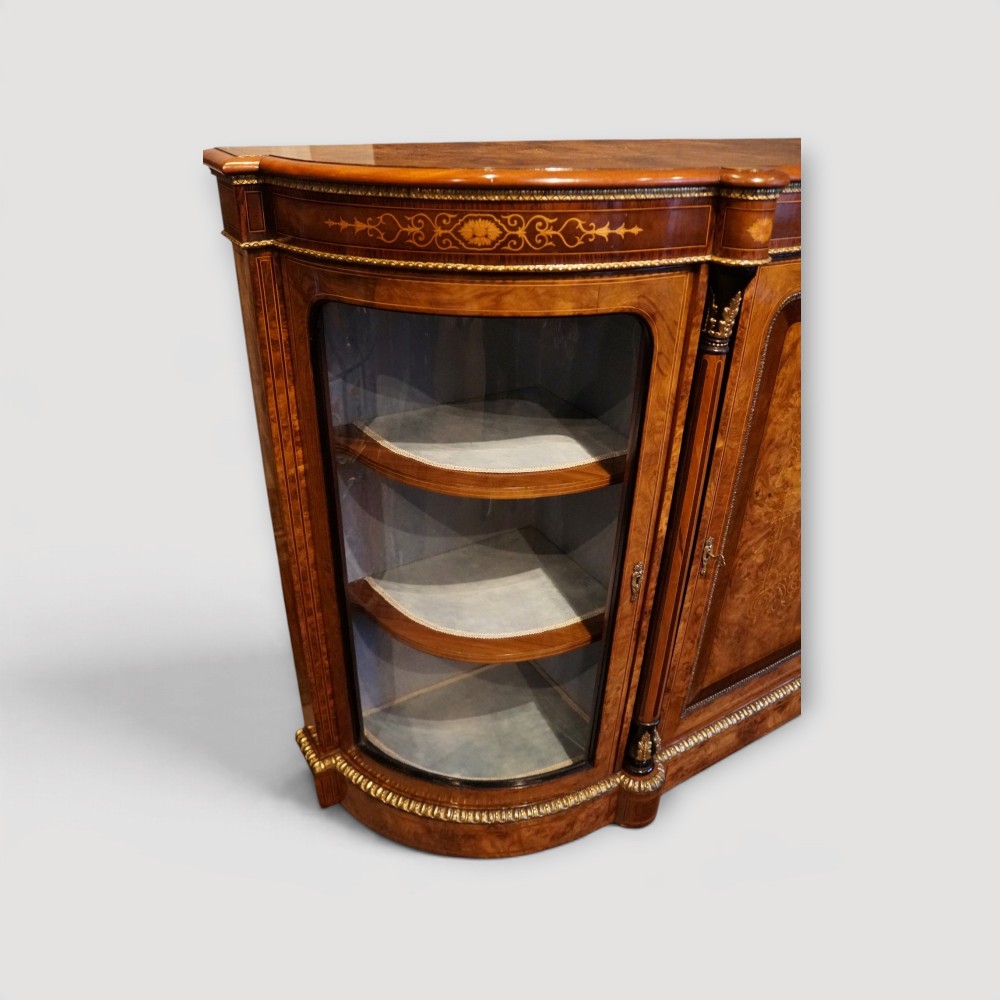 A Victorian burr walnut credenza featuring a central marquetry inlaid door flanked by two curved glazed display side cabinets with gilt mounts. View VIII