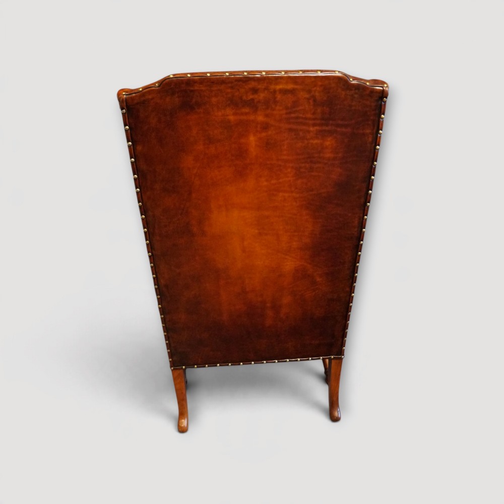 A pair of brown leather Queen Anne style wingback armchairs featuring deep seat cushions, brass stud detailing, and carved walnut cabriole legs. View VIII