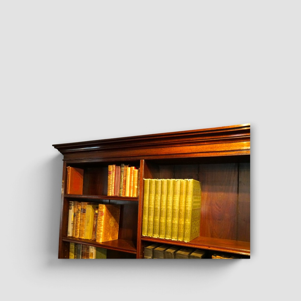 An Edwardian mahogany breakfront bookcase featuring an open upper shelving section filled with books and an enclosed lower cupboard base. View II
