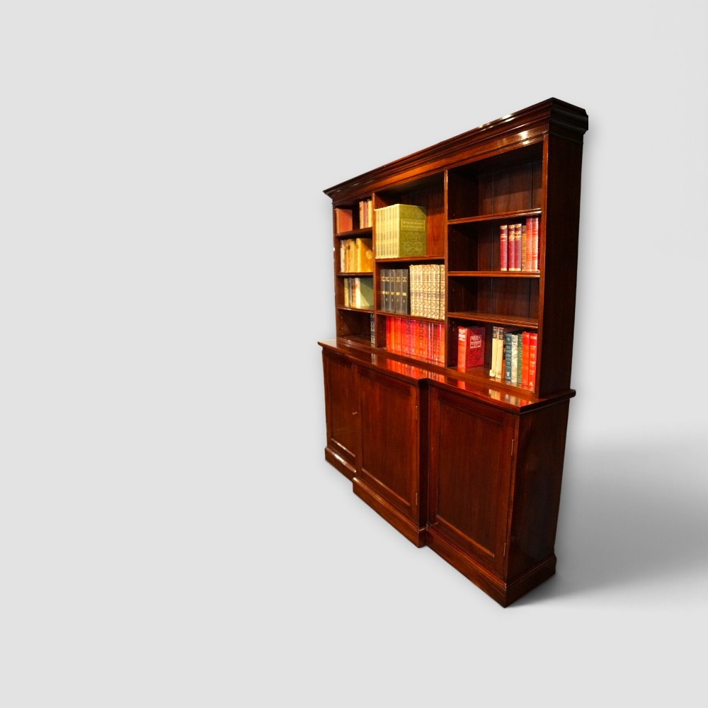 An Edwardian mahogany breakfront bookcase featuring an open upper shelving section filled with books and an enclosed lower cupboard base. View V
