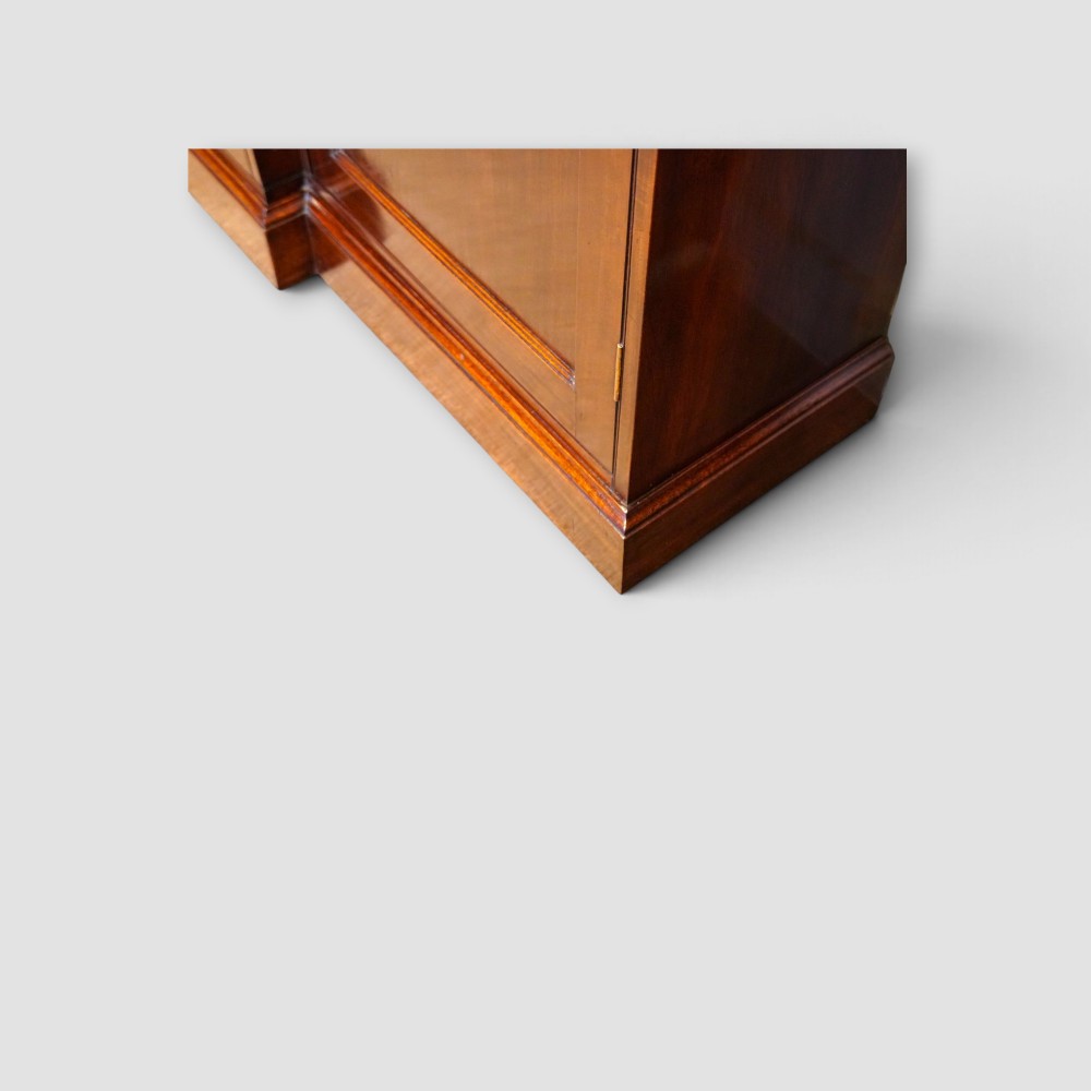 An Edwardian mahogany breakfront bookcase featuring an open upper shelving section filled with books and an enclosed lower cupboard base. View VI