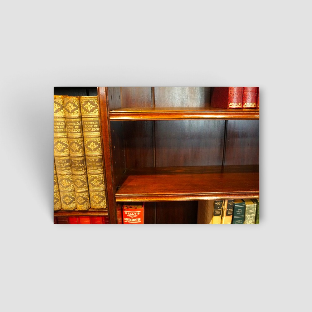 An Edwardian mahogany breakfront bookcase featuring an open upper shelving section filled with books and an enclosed lower cupboard base. View VII