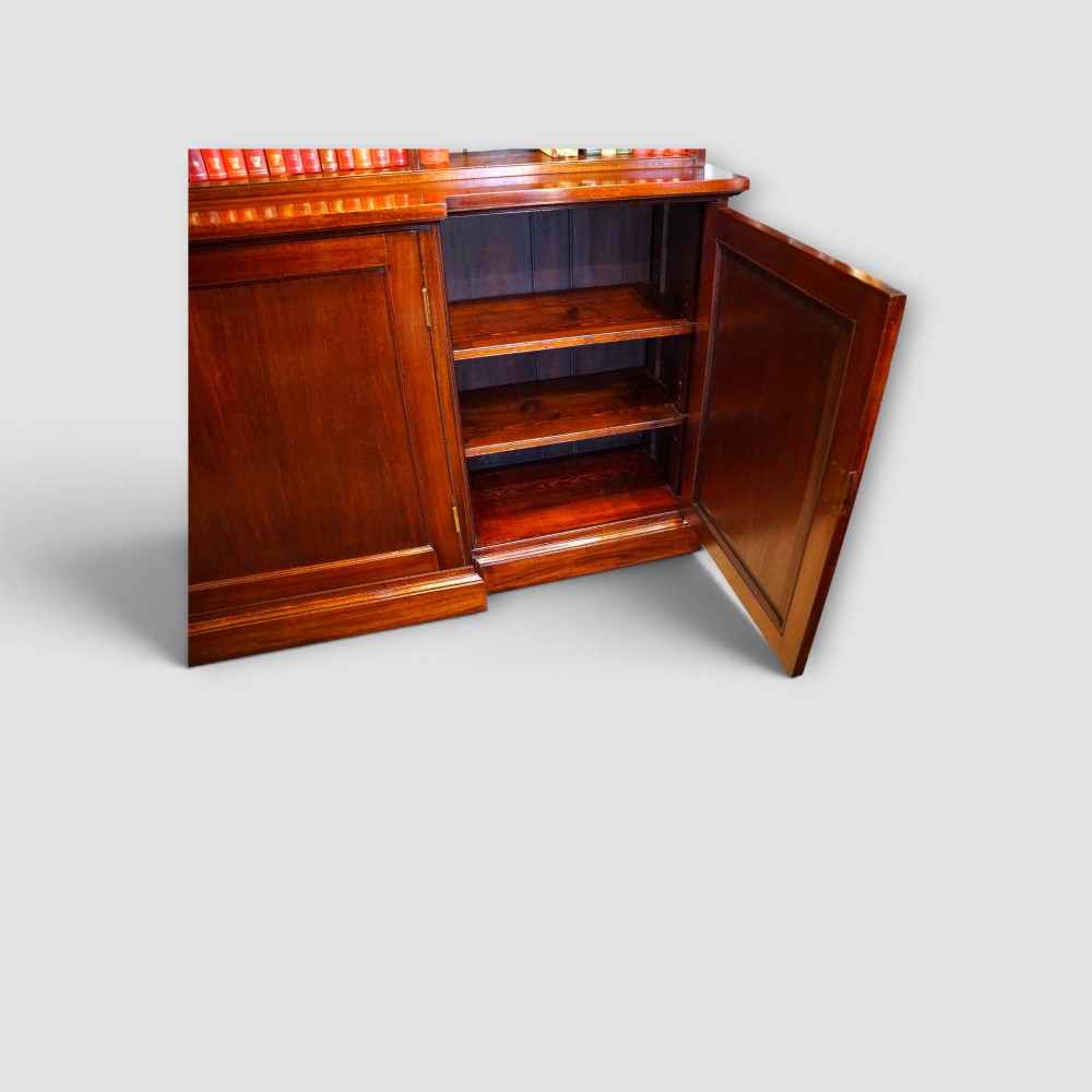 An Edwardian mahogany breakfront bookcase featuring an open upper shelving section filled with books and an enclosed lower cupboard base. View XII