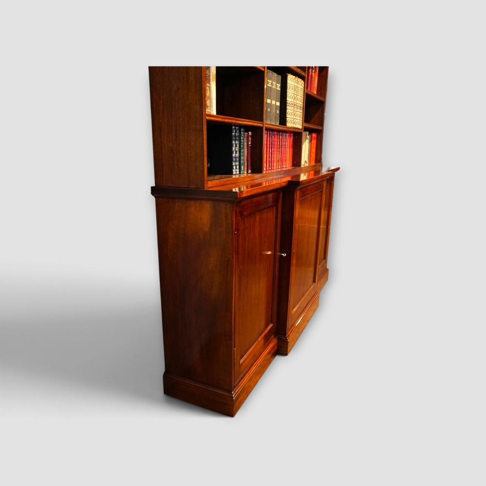An Edwardian mahogany breakfront bookcase featuring an open upper shelving section filled with books and an enclosed lower cupboard base. View XIII