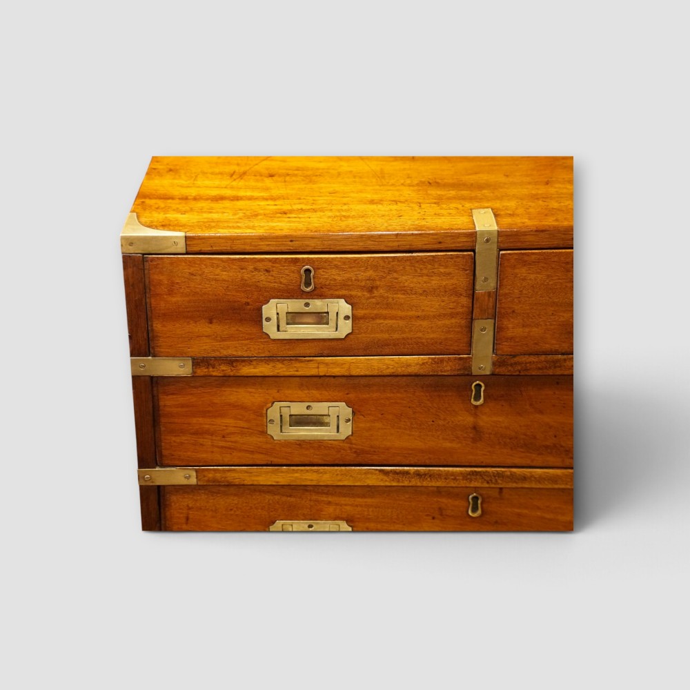 A wooden chest of drawers featuring brass corner brackets, flush handles, and two short drawers above three long drawers. View III